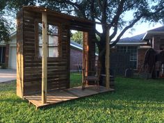 a wooden shed sitting on top of a lush green field next to a tree in front of a house