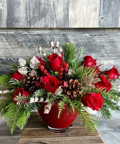 a red vase filled with flowers on top of a wooden table