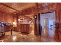 a living room with wood paneling and a grand piano in the middle of it