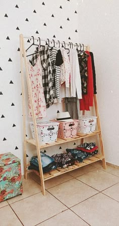 a clothing rack with clothes hanging on it in front of a wall decorated with black and white triangles