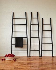 a bowl of cherries sitting on top of a wooden floor next to two ladders