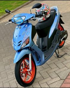 a blue scooter parked on top of a brick sidewalk