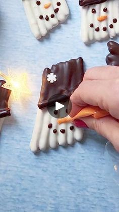 someone is decorating small chocolate snowmen with carrots and marshmallows