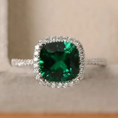 an emerald colored stone surrounded by white diamonds