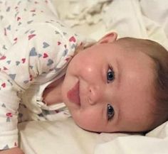 a smiling baby laying on top of a bed