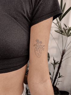 a woman with a heart tattoo on her left arm and the other arm behind her