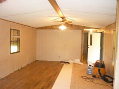 an unfinished room with wood floors and ceiling fan