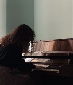 a woman sitting at a piano with long curly hair