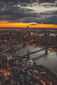 an aerial view of a city at night with the lights on and bridge in the foreground