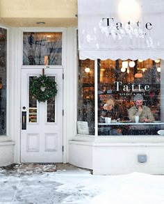 two people sitting at a table in front of a store window on a snowy day