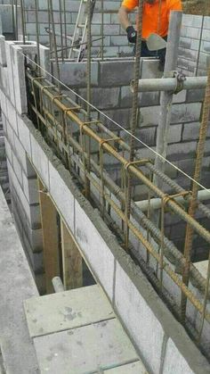 a man in an orange shirt is working on a construction site with concrete blocks and steel bars