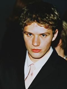 a young man in a suit and tie looking at the camera with an intense look on his face