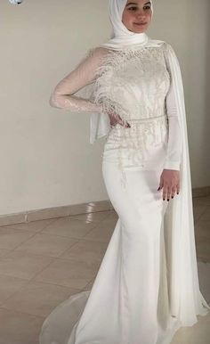 a woman in a white dress and veil posing for the camera with her hands on her hips