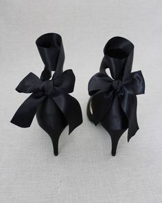 two pairs of black shoes with bows on them