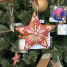 a red star ornament hanging from a christmas tree