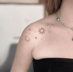 a woman wearing a black dress has a small tattoo on her left shoulder and the sun and moon are visible