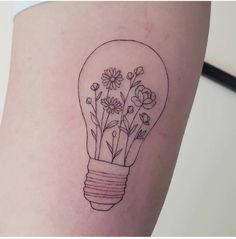 a light bulb with flowers in it is on the thigh and has a tattoo design