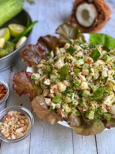 a salad with lettuce and other ingredients on a white plate next to bowls