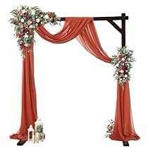 an orange wedding arch decorated with flowers and greenery