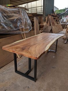 a table made out of wood and metal legs in a warehouse with lots of wooden planks