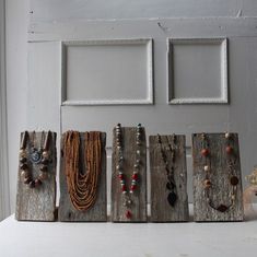 five pieces of wood with beaded necklaces hanging from them on a shelf in front of a door