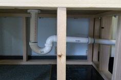 an open cabinet with pipes running through it