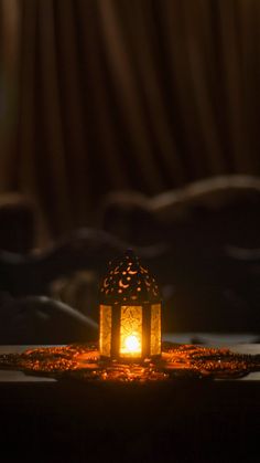 a lit lantern on a bed in the dark