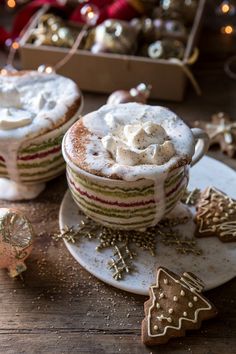 two cupcakes with white frosting on them sitting on a plate next to christmas decorations