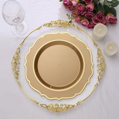 a white table topped with a gold plate and wine glasses