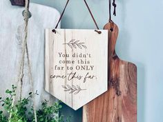 a wooden sign hanging from the side of a wall next to a potted plant