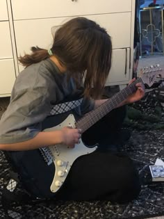 a person sitting on the ground playing an electric guitar