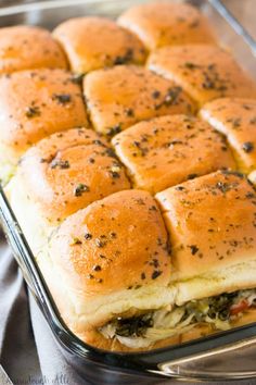 a casserole dish filled with chicken, cheese and bread rolls covered in seasoning