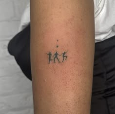 a person with a tattoo on their arm that has three small people in the middle