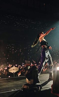 a woman standing on top of a stage next to a man with his arms in the air