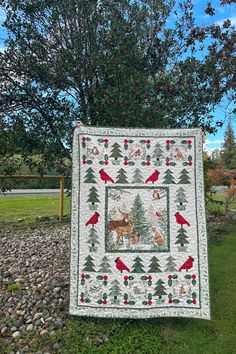 a quilted christmas tree with birds and deer on it in front of a green field