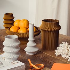 there are three vases on the table with oranges and other things around them