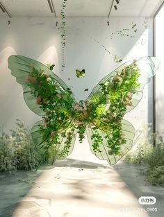 a large butterfly made out of leaves and flowers in a room with plants on the floor