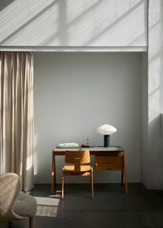 a desk and chair in a room with sunlight coming through the window onto the floor