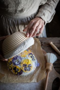 a woman is making a cake with flowers on it