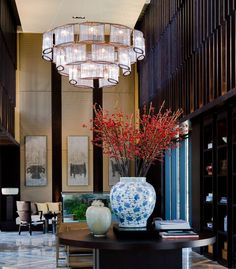 a vase with red flowers is sitting on a table in front of a chandelier