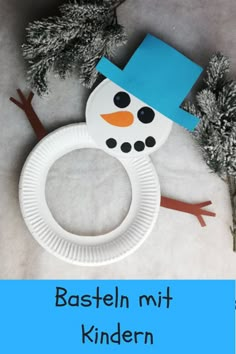 a paper plate with a snowman on it next to some branches and pine cones