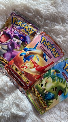 four pokemon trading cards laying on top of a white fur covered bedding with the covers pulled back