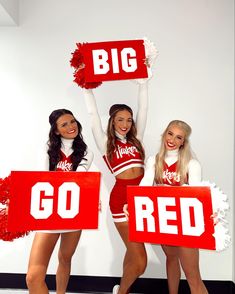 three cheerleaders are holding up signs that say go red and the word big is written on them