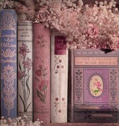 some books are lined up on a shelf with flowers in the middle and one is empty