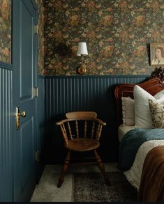 a bed room with a neatly made bed and a wooden chair next to the door