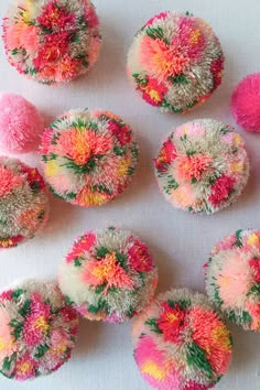 several different colored pom poms on a white surface