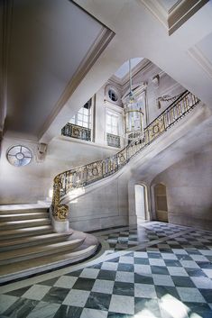 an ornate staircase and chandelier in a large room with checkered flooring