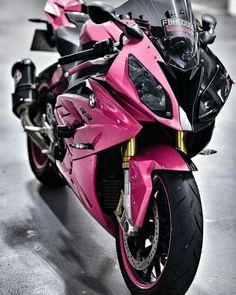 a pink and black motorcycle parked in a garage