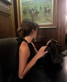 a woman sitting at a table in front of a purse