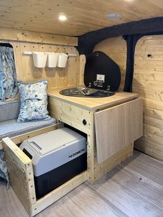 the interior of a small camper with wood paneling and blue pillows on it